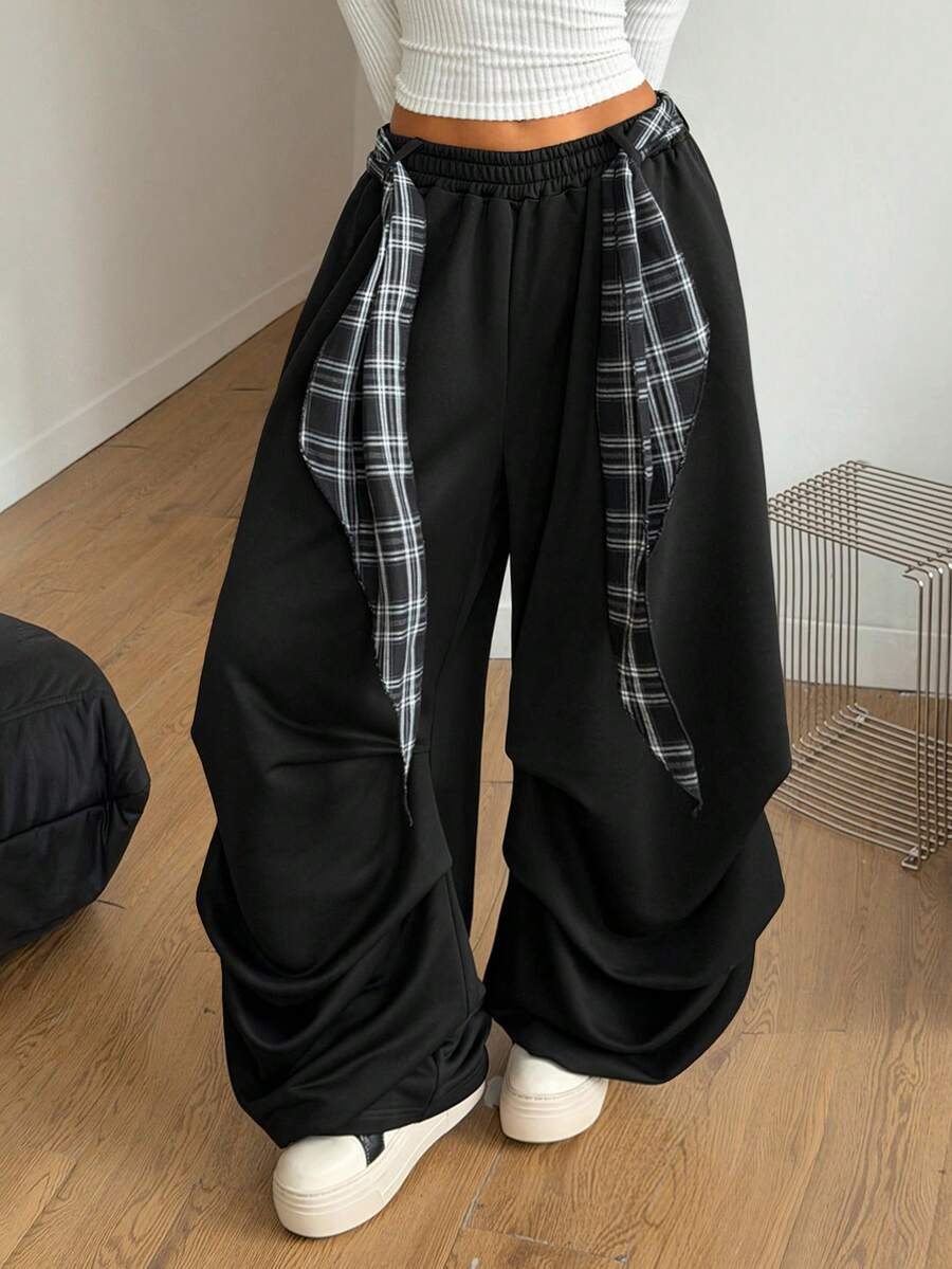 Loose-fitting black baggy parachute pants featuring an elastic drawstring waistband and wide-leg cut made from cotton blend fabric.