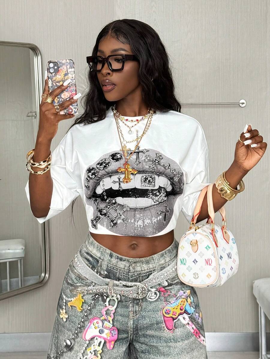 Front view of a women's black oversized crop t-shirt with pink lips graphic, round neckline, and short drop-shoulder sleeves.
