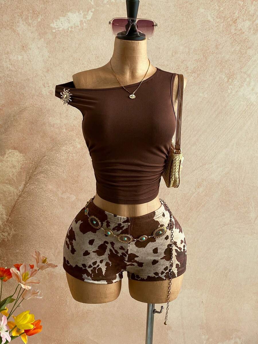 Women's black fuzzy knit two-piece set with an asymmetrical crop camisole top featuring ruched detail and cutout back, paired with matching mini shorts.