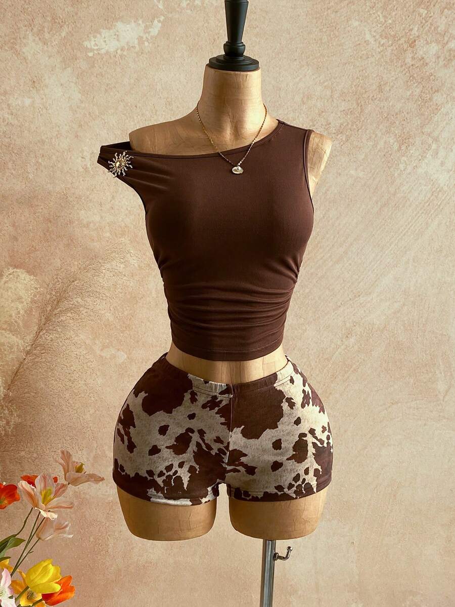 Women's black fuzzy knit two-piece set with an asymmetrical crop camisole top featuring ruched detail and cutout back, paired with matching mini shorts.