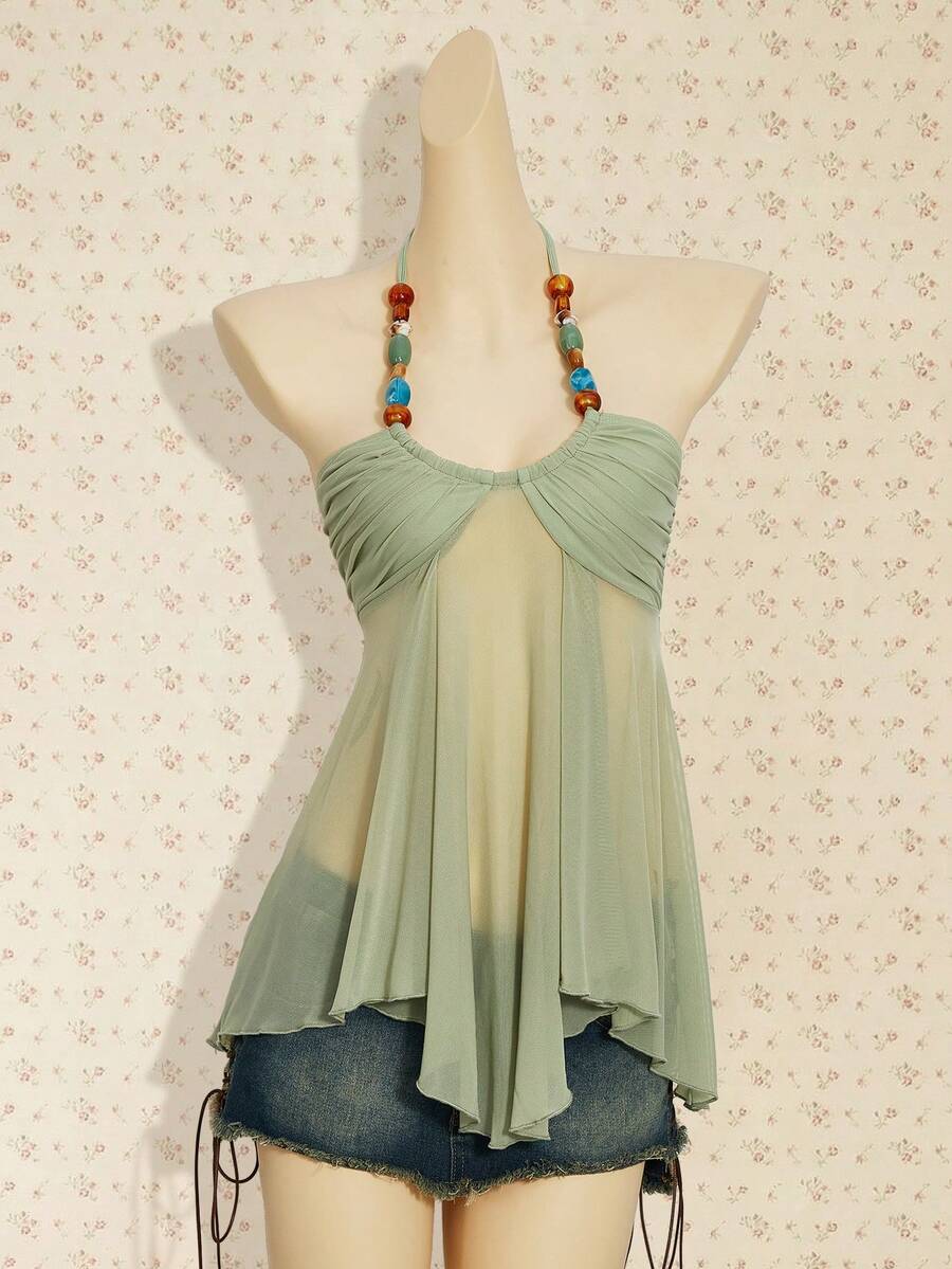Women's boho halter mesh tank top with asymmetrical hem, semi-sheer finish, lined body, slim fit, and cold shoulder styling.