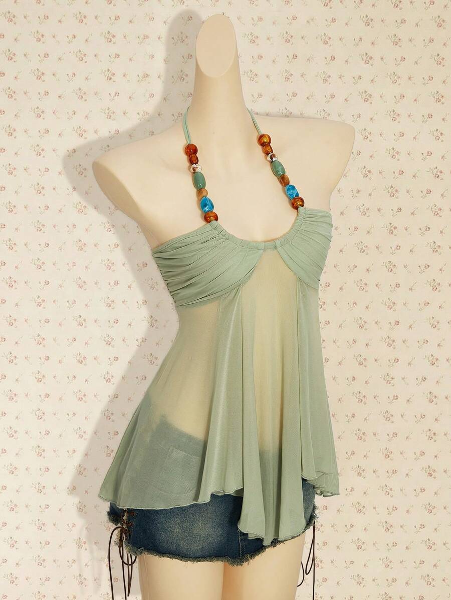 Women's boho halter mesh tank top with asymmetrical hem, semi-sheer finish, lined body, slim fit, and cold shoulder styling.