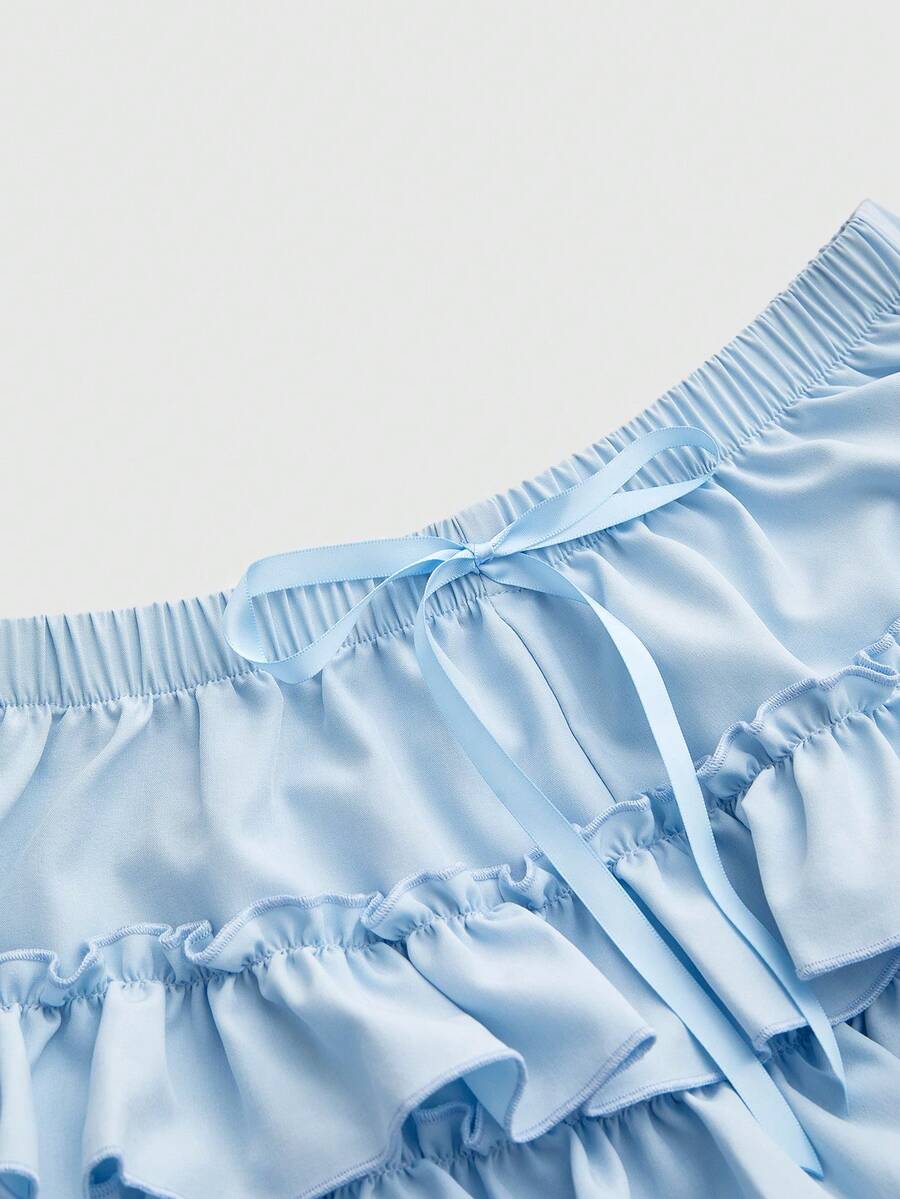 Women's tiered ruffle skort shorts featuring an elastic mid waist with front tie knot detail in woven fabric.