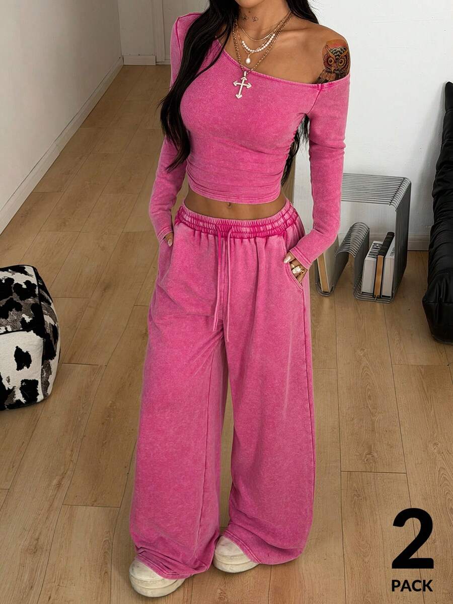 Women's two-piece knit lounge set featuring a black long sleeve asymmetrical crop top and matching high-waisted wide leg sweatpants.