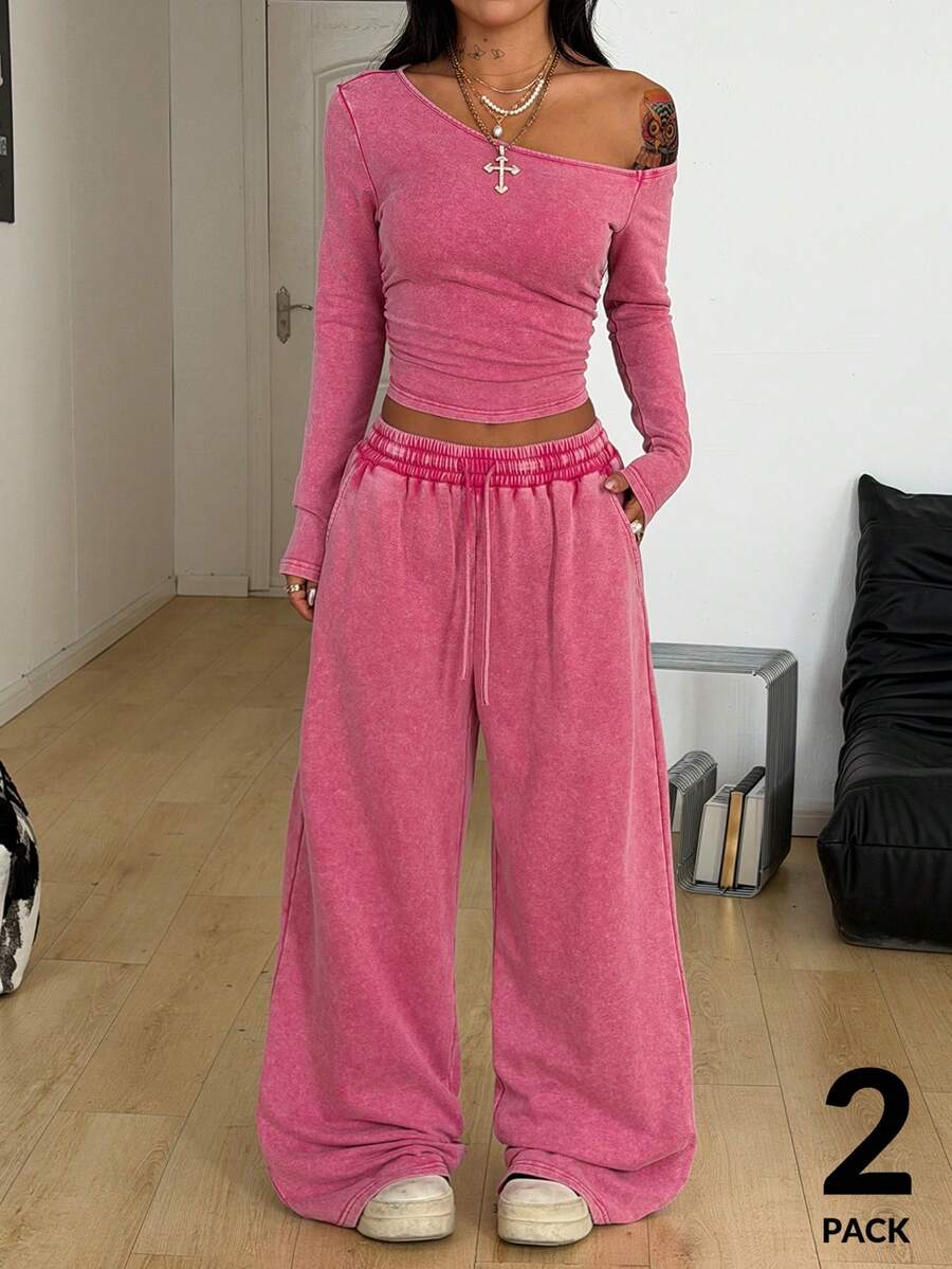 Women's two-piece knit lounge set featuring a black long sleeve asymmetrical crop top and matching high-waisted wide leg sweatpants.