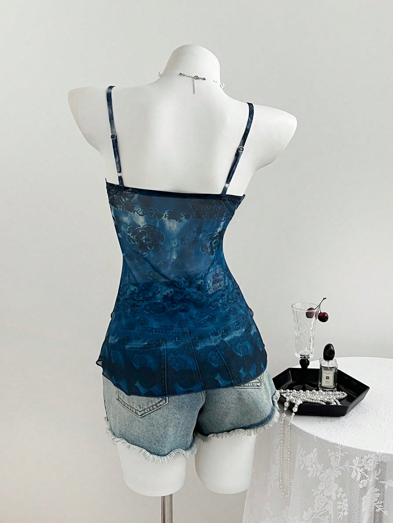 Women's boho spaghetti strap cami with multicolor all-over plant print, contrast lace detail, ruffle tiered hem, and slim fit silhouette.
