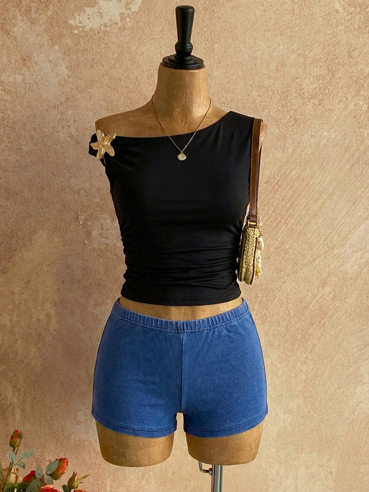 Women's black fuzzy knit two-piece set with an asymmetrical crop camisole top featuring ruched detail and cutout back, paired with matching mini shorts.