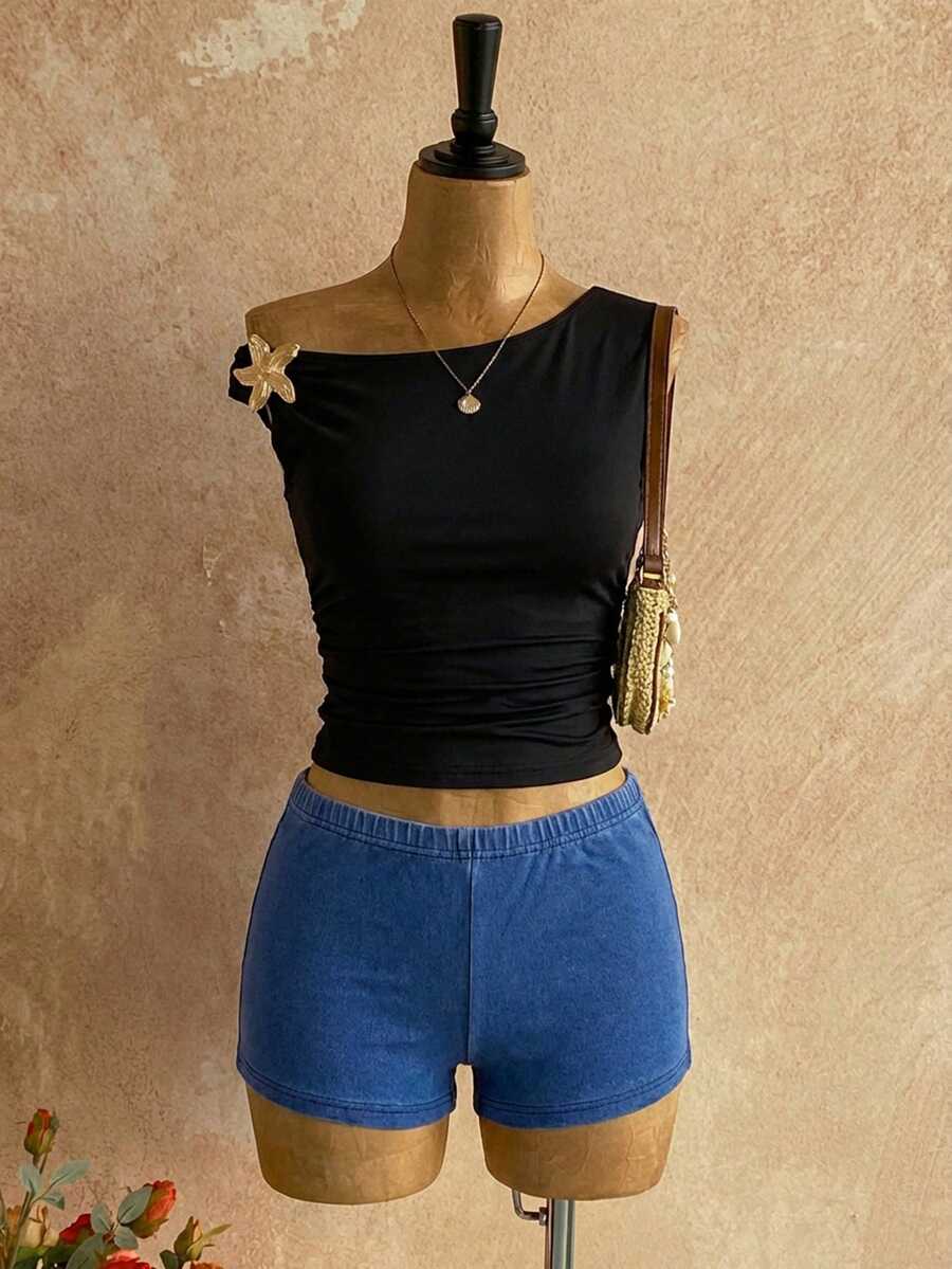 Women's black fuzzy knit two-piece set with an asymmetrical crop camisole top featuring ruched detail and cutout back, paired with matching mini shorts.