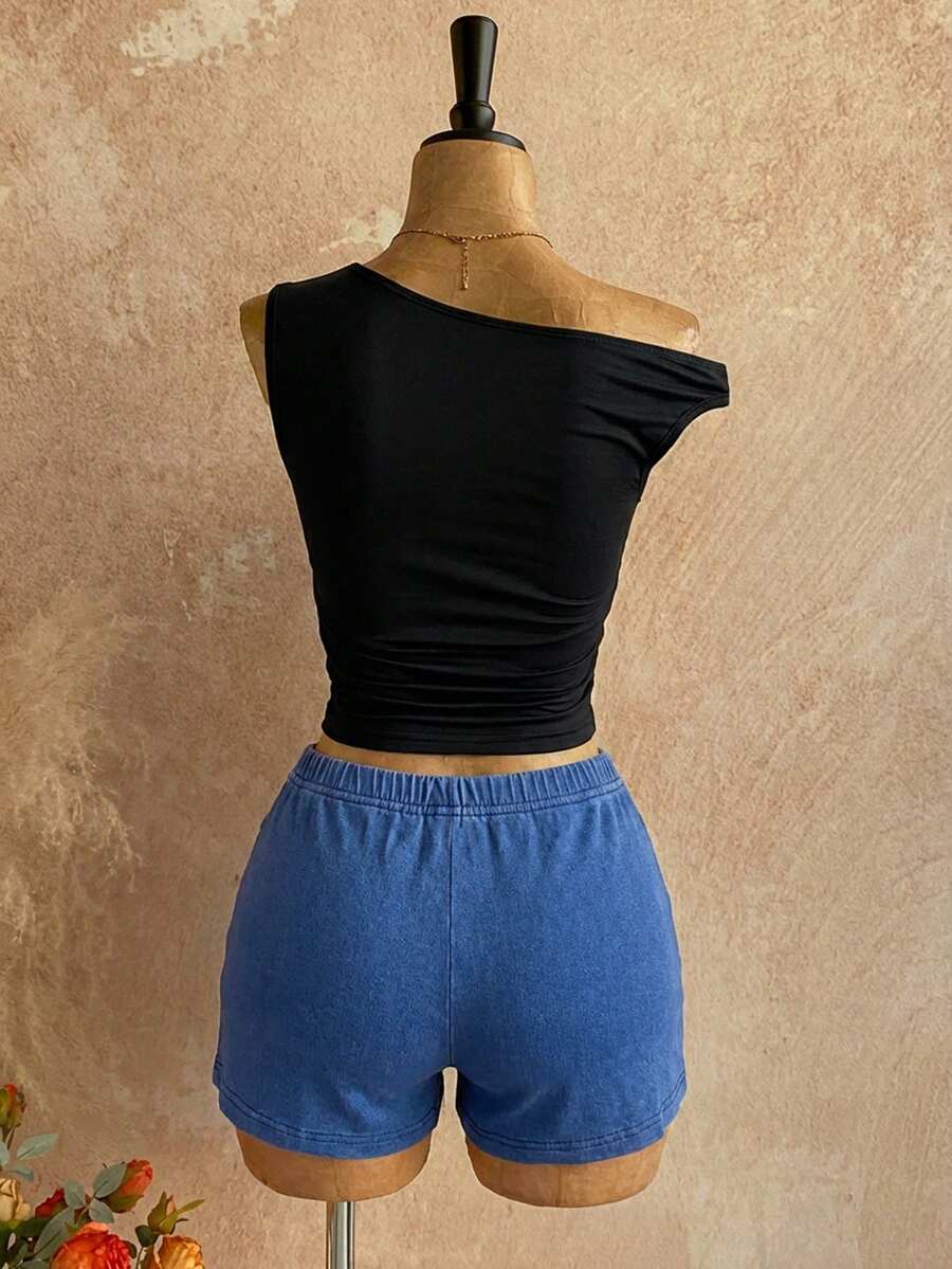 Women's black fuzzy knit two-piece set with an asymmetrical crop camisole top featuring ruched detail and cutout back, paired with matching mini shorts.