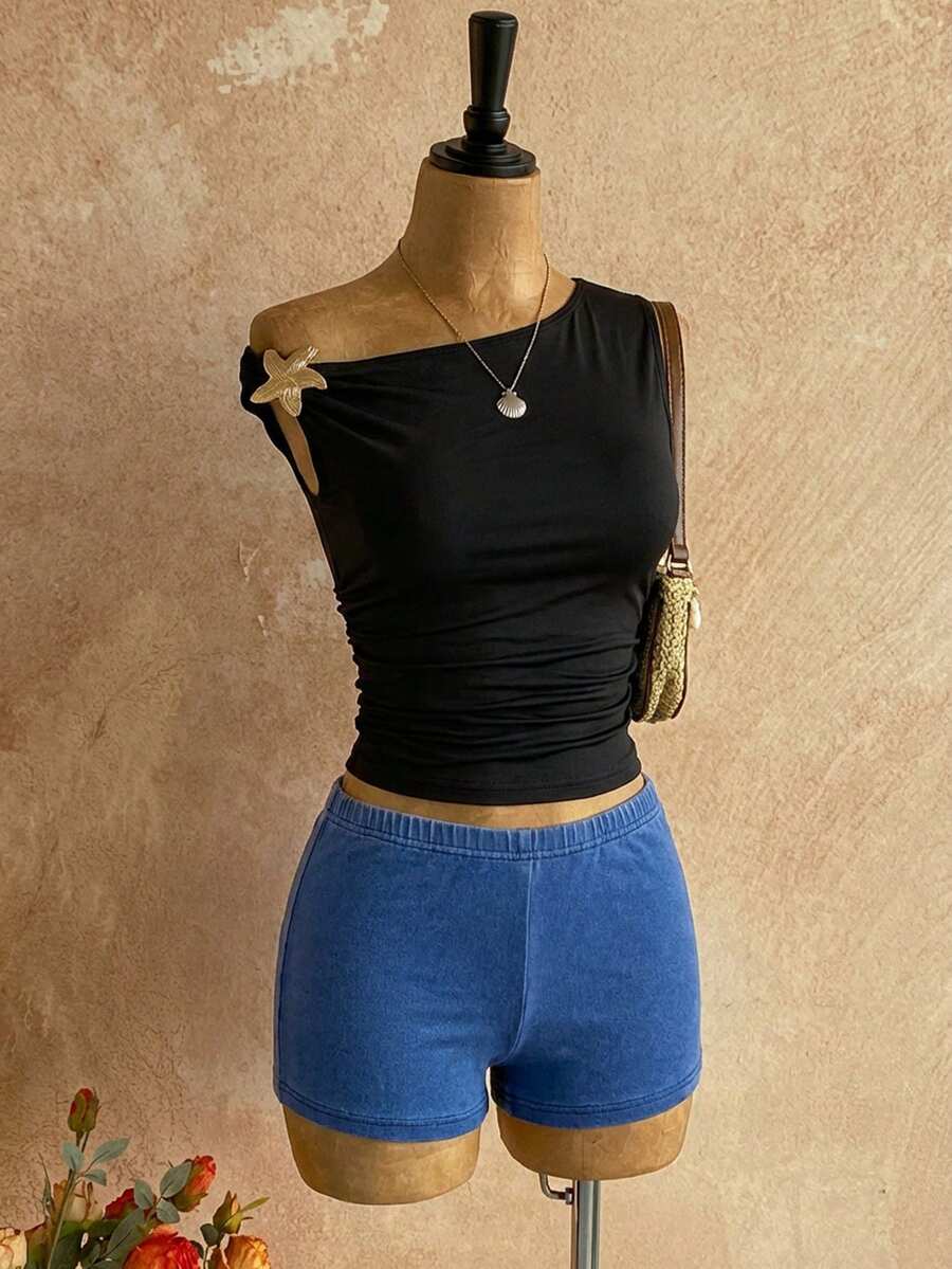 Women's black fuzzy knit two-piece set with an asymmetrical crop camisole top featuring ruched detail and cutout back, paired with matching mini shorts.