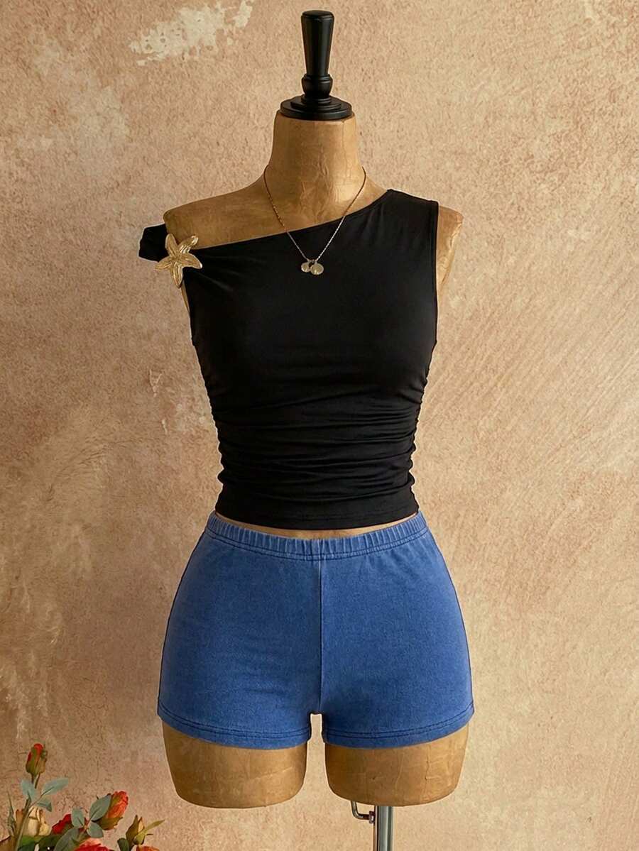 Women's black fuzzy knit two-piece set with an asymmetrical crop camisole top featuring ruched detail and cutout back, paired with matching mini shorts.