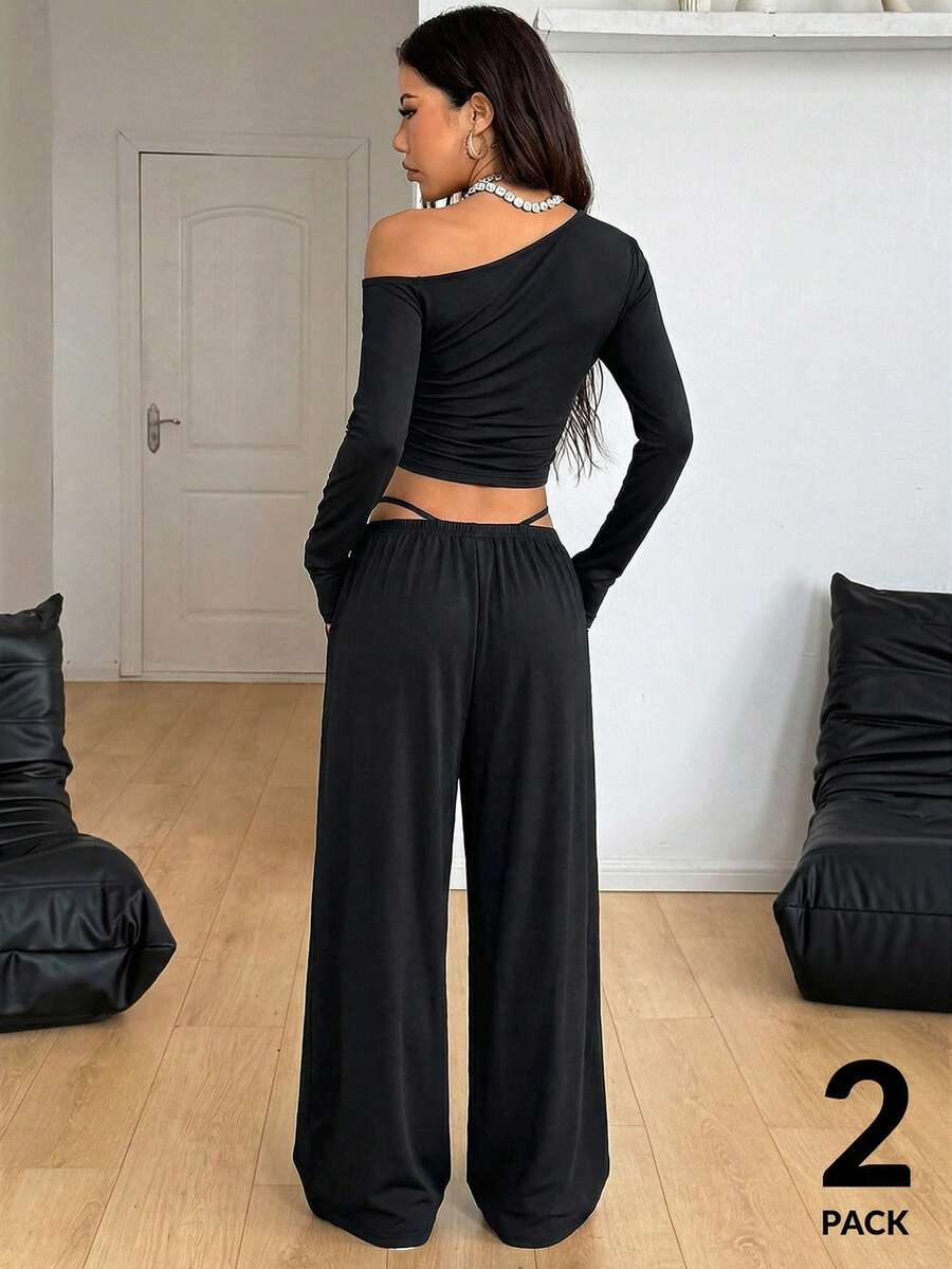 Women's two-piece knit lounge set featuring a black long sleeve asymmetrical crop top and matching high-waisted wide leg sweatpants.