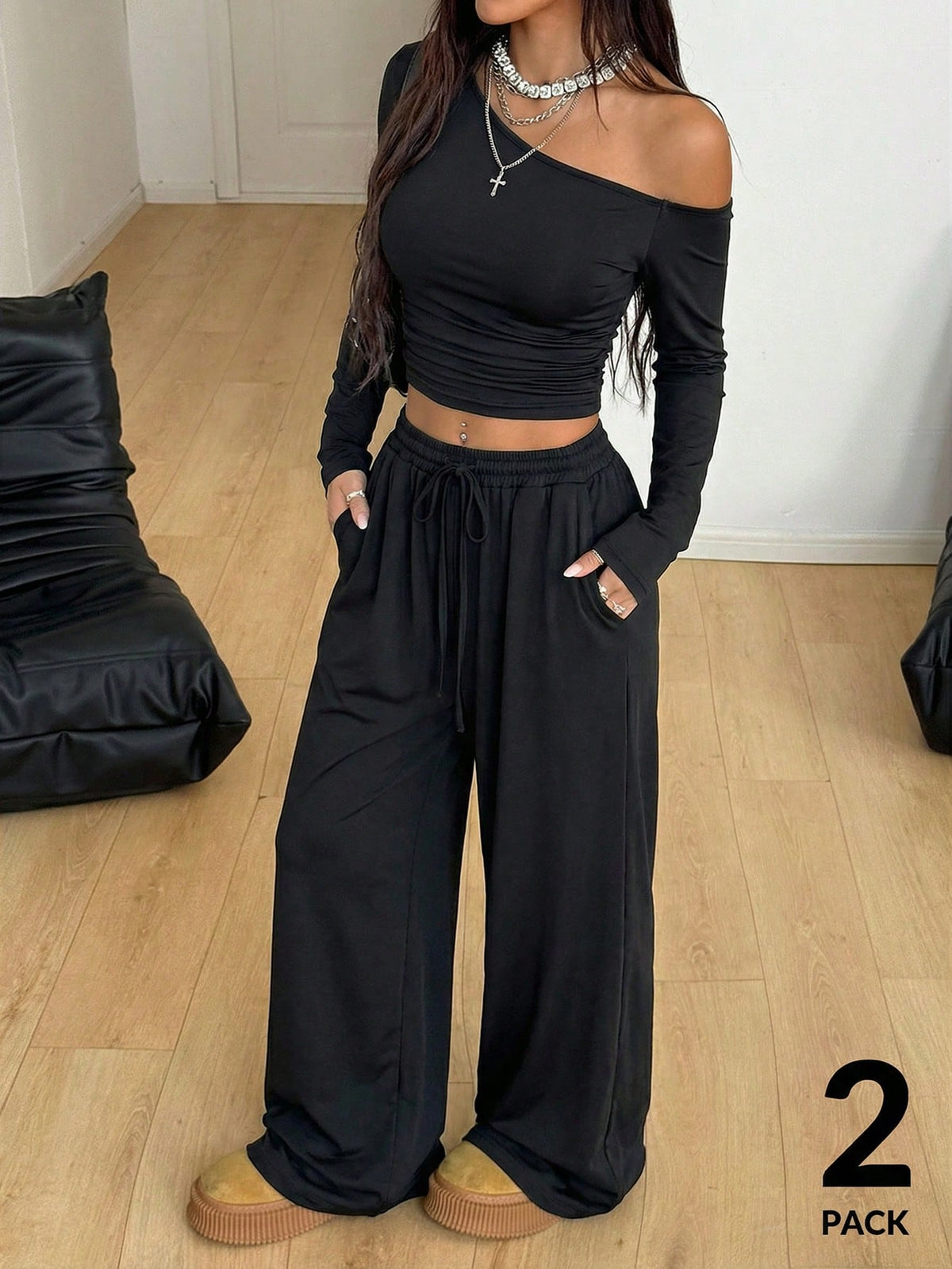 Women's two-piece knit lounge set featuring a black long sleeve asymmetrical crop top and matching high-waisted wide leg sweatpants.