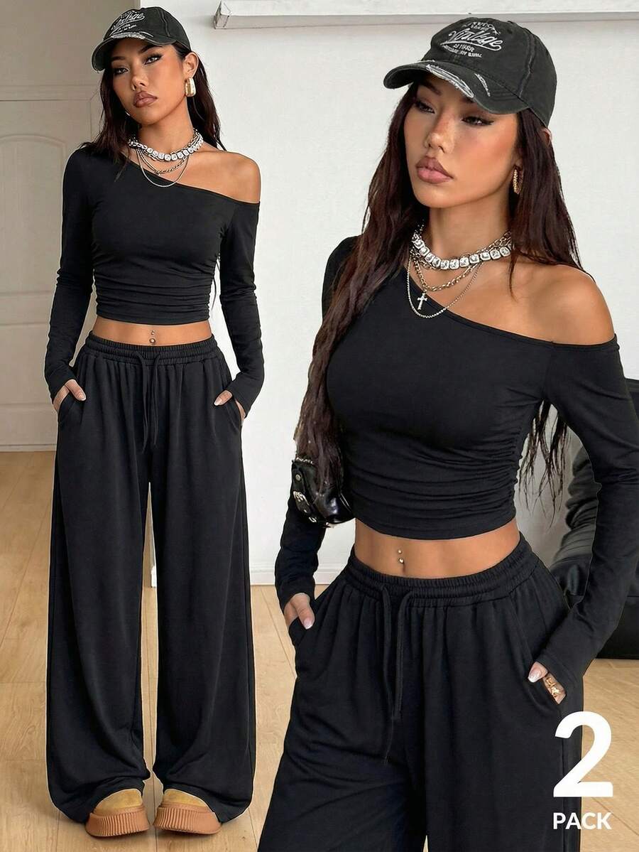 Women's two-piece knit lounge set featuring a black long sleeve asymmetrical crop top and matching high-waisted wide leg sweatpants.