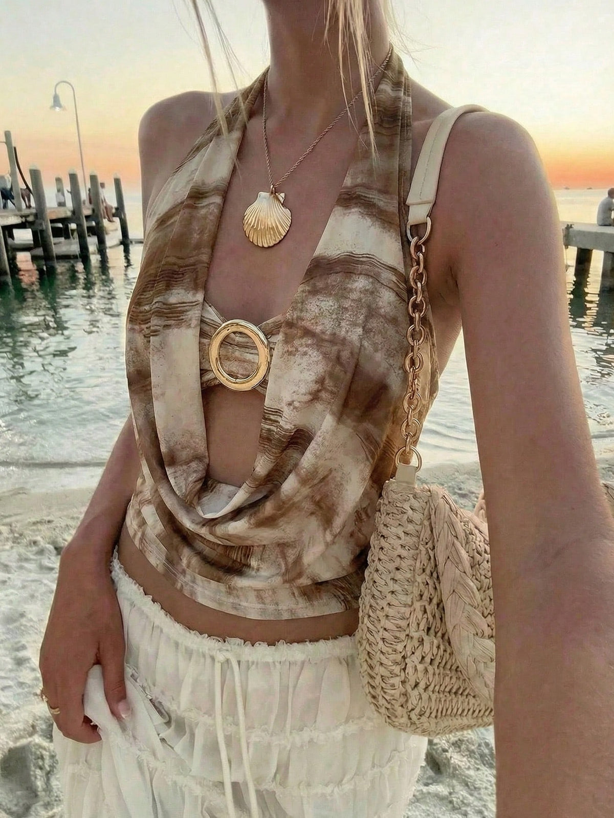 Brown and white polka dot semi-sheer halter camisole top with a plunging neckline, backless design, draped front, and metallic studded embellishments.
