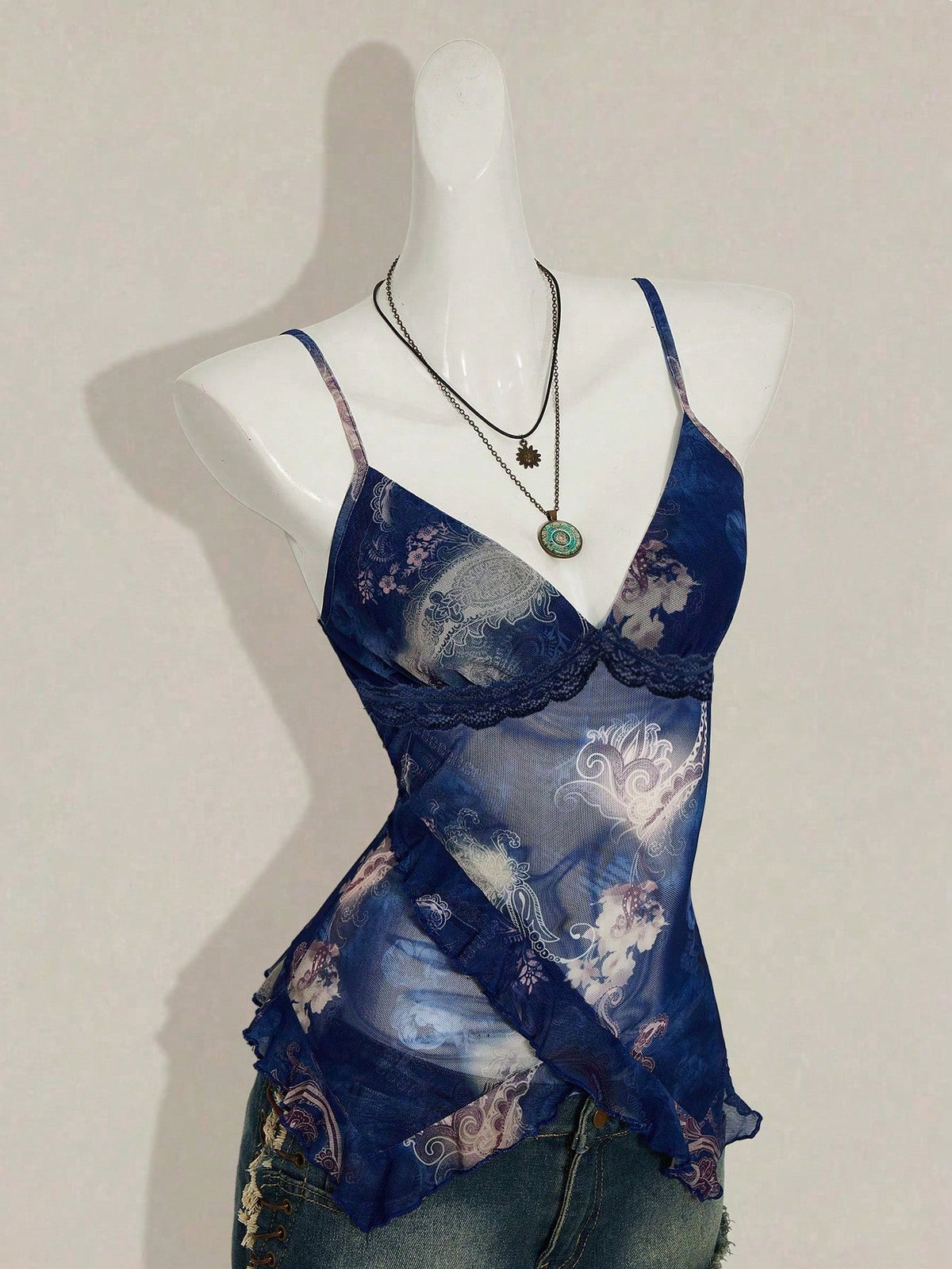 Women's graphic print camisole top featuring thin spaghetti straps, a backless cut, and an asymmetrical hem.