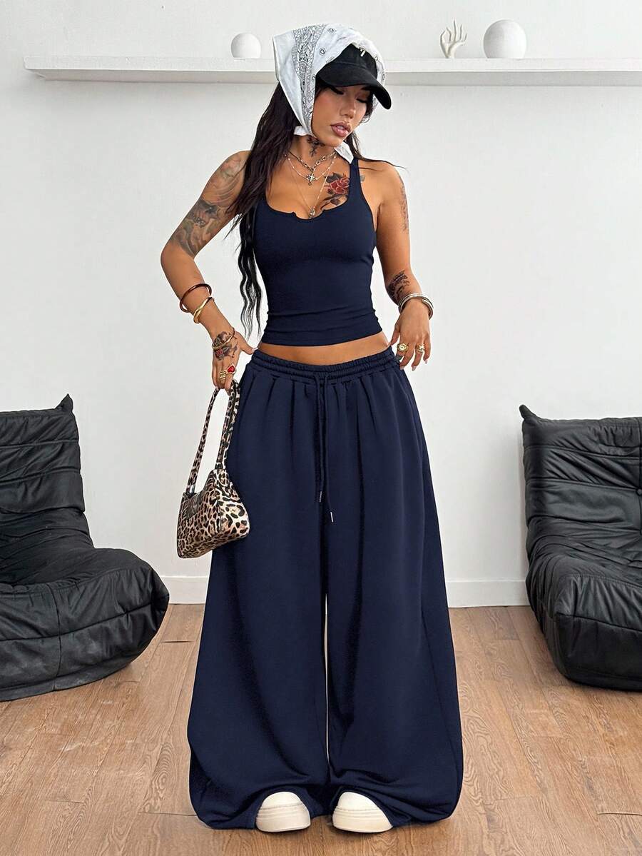 Women's two-piece casual outfit featuring a slim-fit camisole tank top with ruffle trim and button front paired with high-waisted wide leg pants.