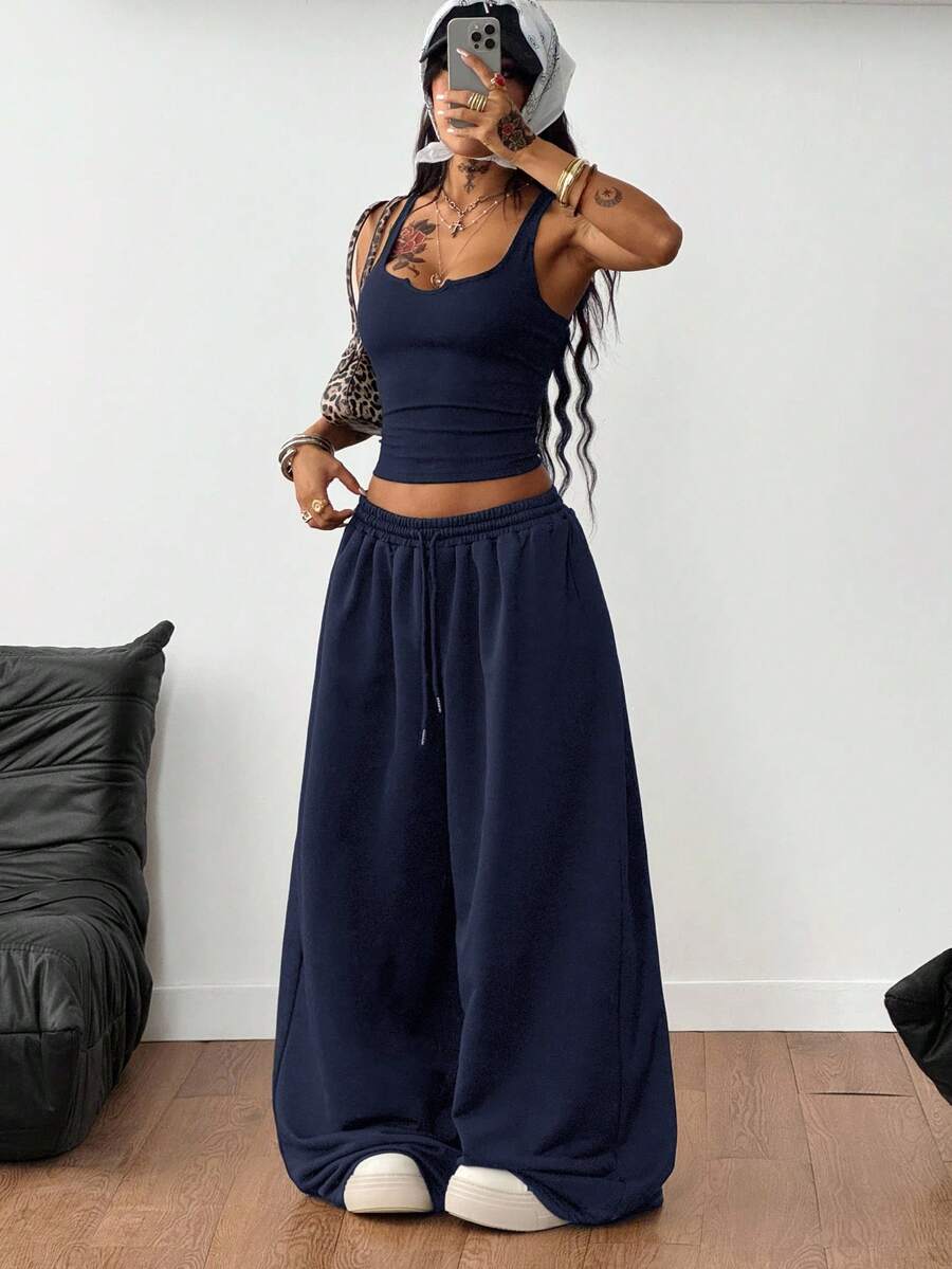 Women's two-piece casual outfit featuring a slim-fit camisole tank top with ruffle trim and button front paired with high-waisted wide leg pants.