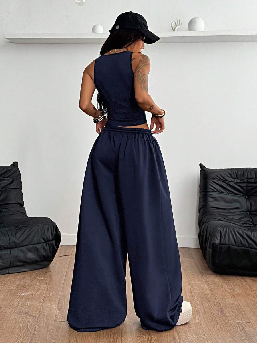 Women's two-piece casual outfit featuring a slim-fit camisole tank top with ruffle trim and button front paired with high-waisted wide leg pants.