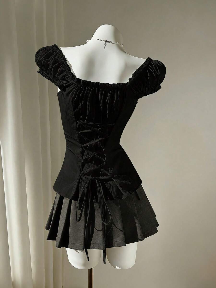 Women's black off-shoulder cap sleeve blouse with ruffled detailing and a tie-back design.