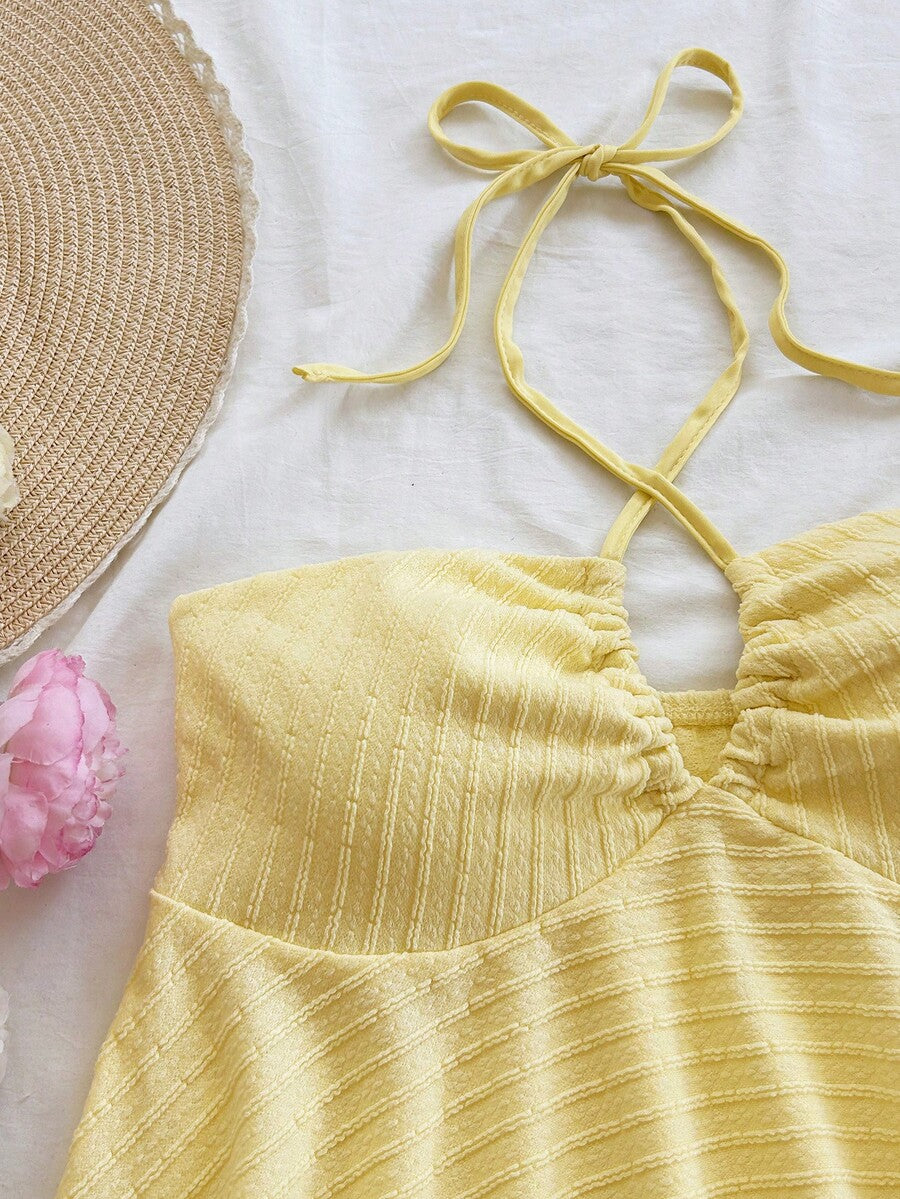 Women's textured V-neck halter tank top with backless knot detail, ruffle hem, and flared silhouette for casual beach and vacation wear.