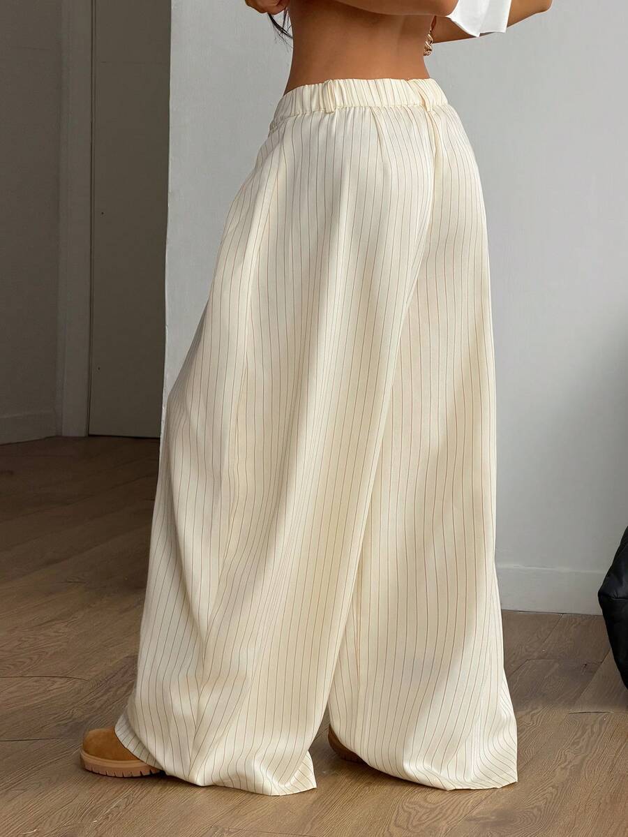 Women's brown striped wide leg pants with a low waist, curved hem, and loose casual fit in woven fabric.