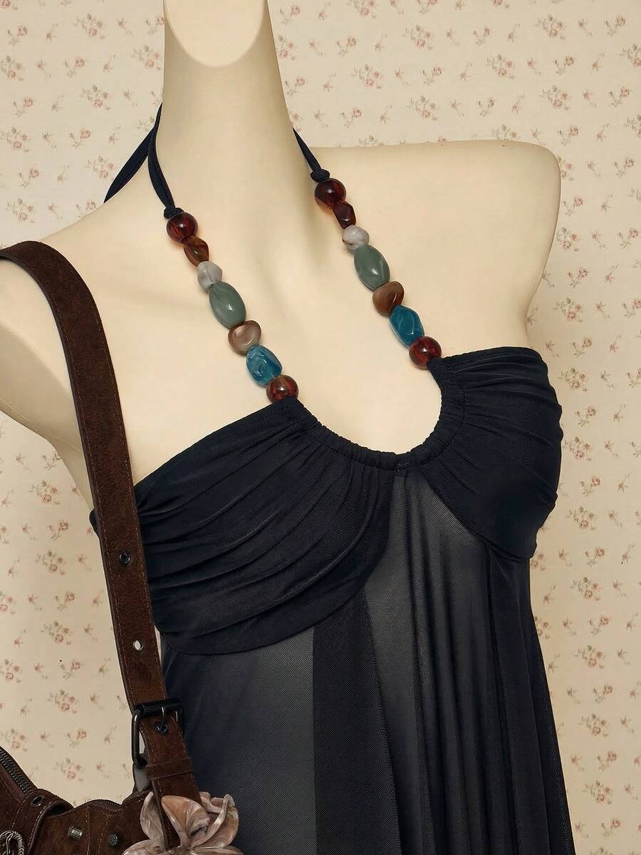 Women's boho halter mesh tank top with asymmetrical hem, semi-sheer finish, lined body, slim fit, and cold shoulder styling.