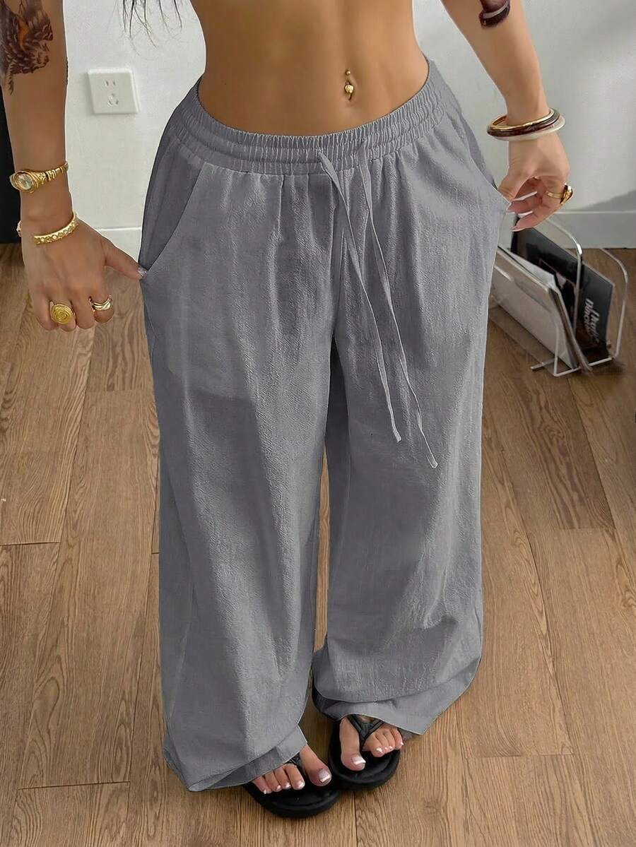 Women's black and white striped wide leg pants featuring an adjustable drawstring waist and side pockets.