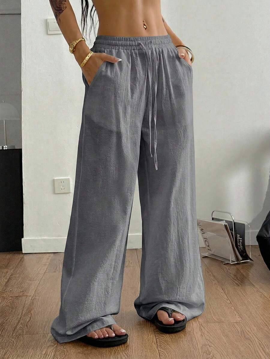 Women's black and white striped wide leg pants featuring an adjustable drawstring waist and side pockets.