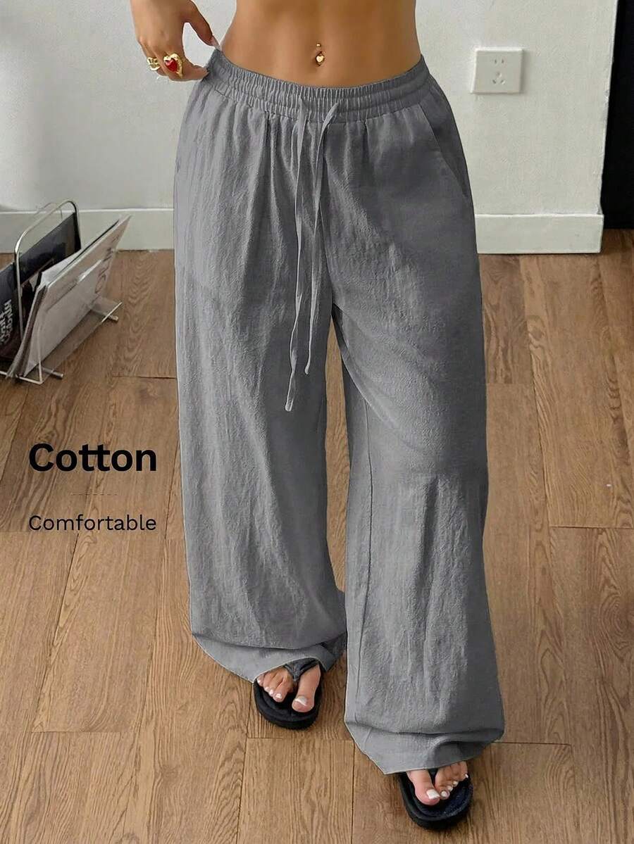 Women's black and white striped wide leg pants featuring an adjustable drawstring waist and side pockets.