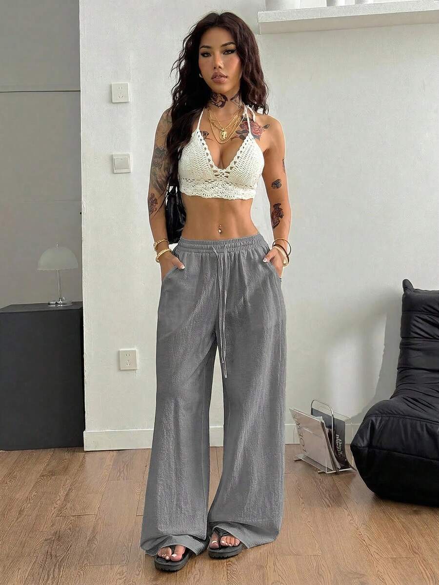 Women's black and white striped wide leg pants featuring an adjustable drawstring waist and side pockets.