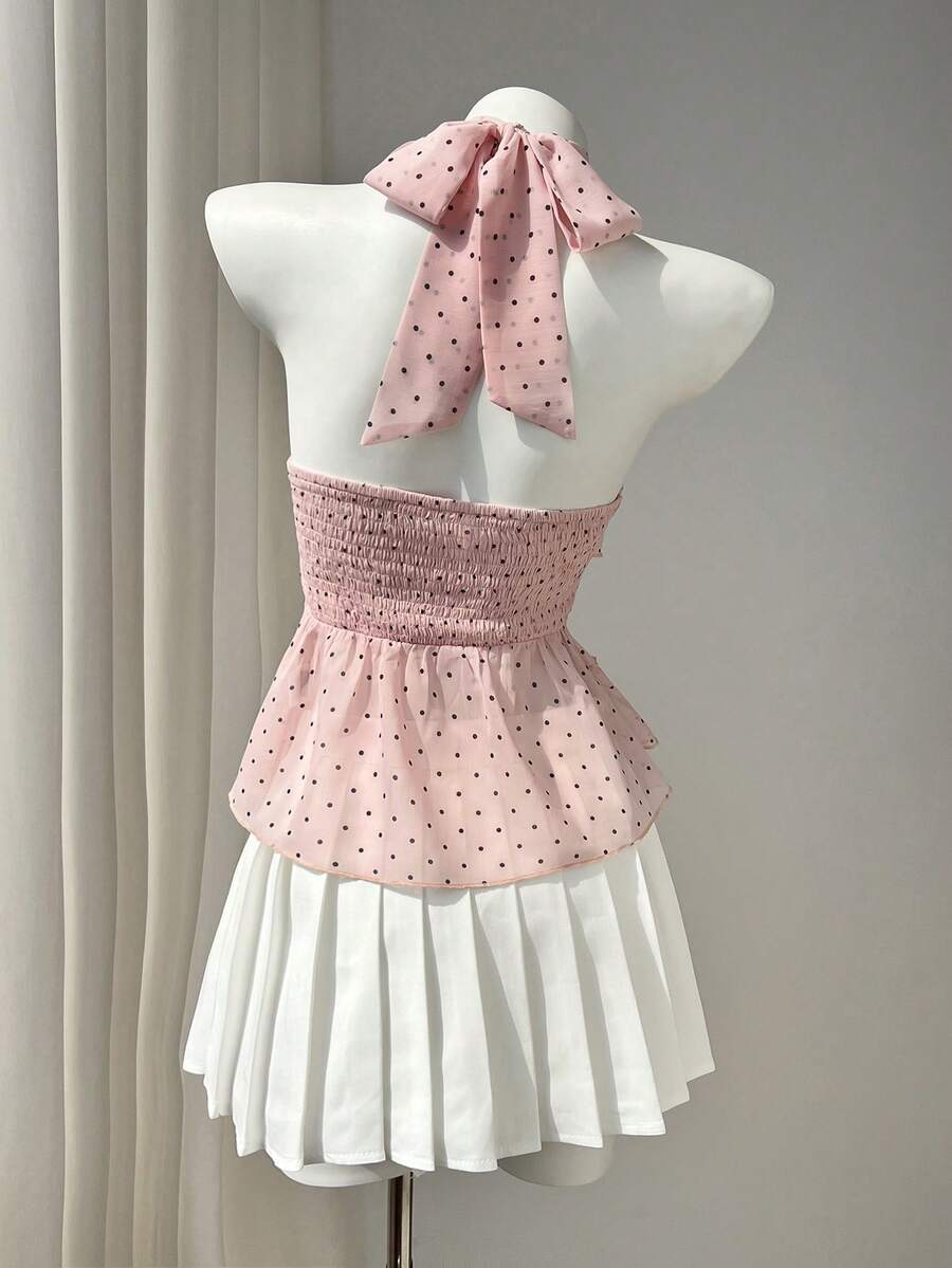 Women's white sleeveless halter neck top featuring pleated fabric, backless tie strap design, and a flared layered ruffle hem.