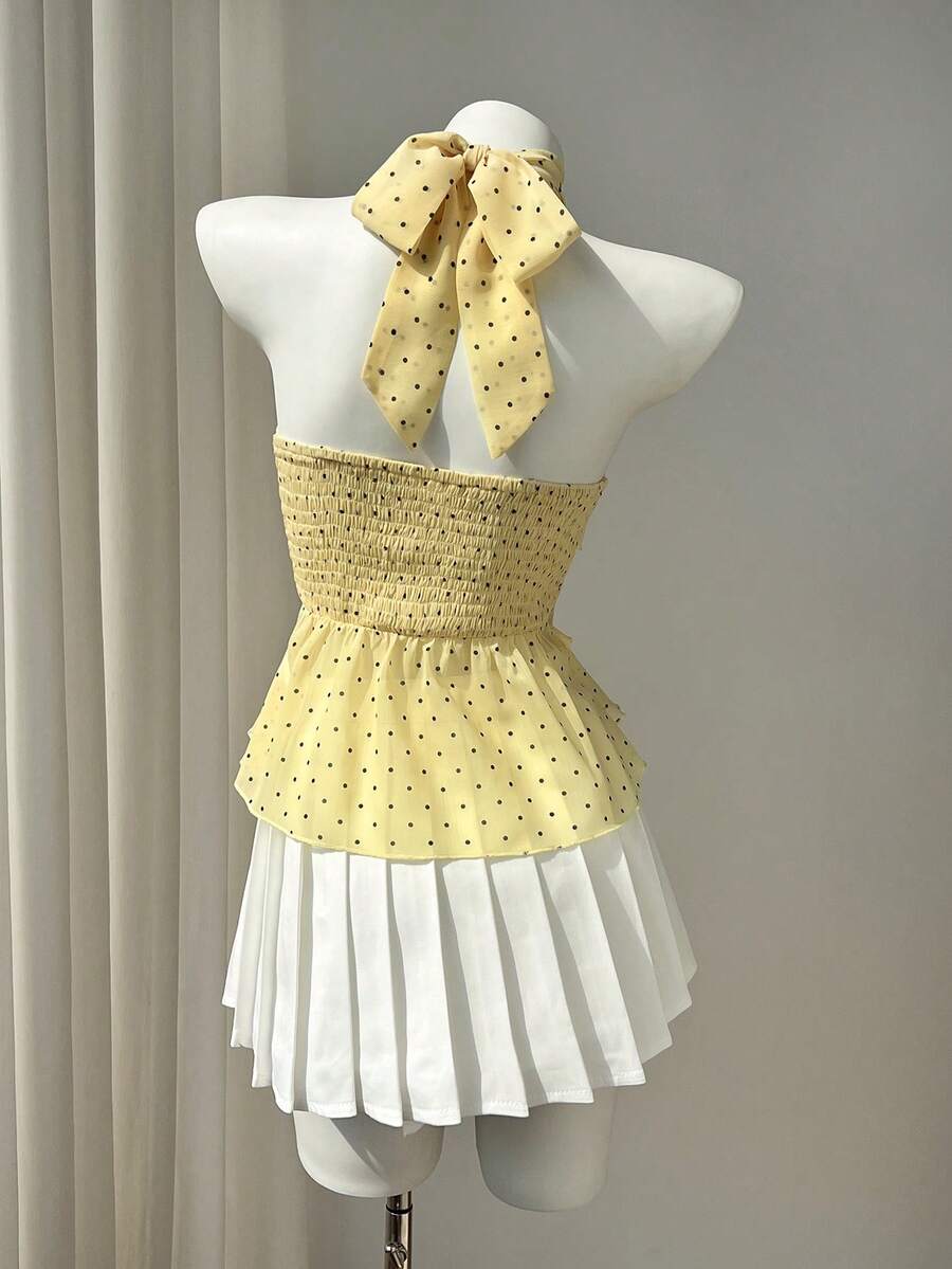 Women's white sleeveless halter neck top featuring pleated fabric, backless tie strap design, and a flared layered ruffle hem.