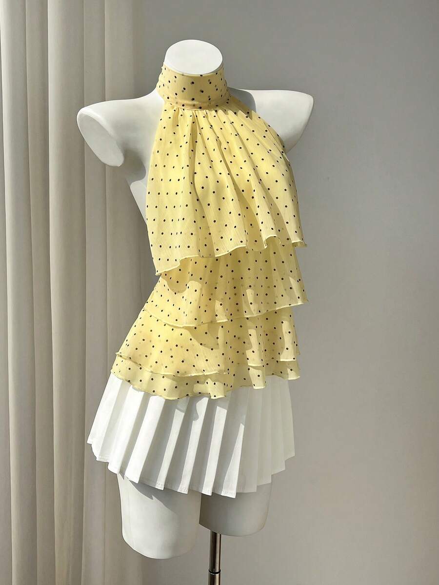 Women's white sleeveless halter neck top featuring pleated fabric, backless tie strap design, and a flared layered ruffle hem.