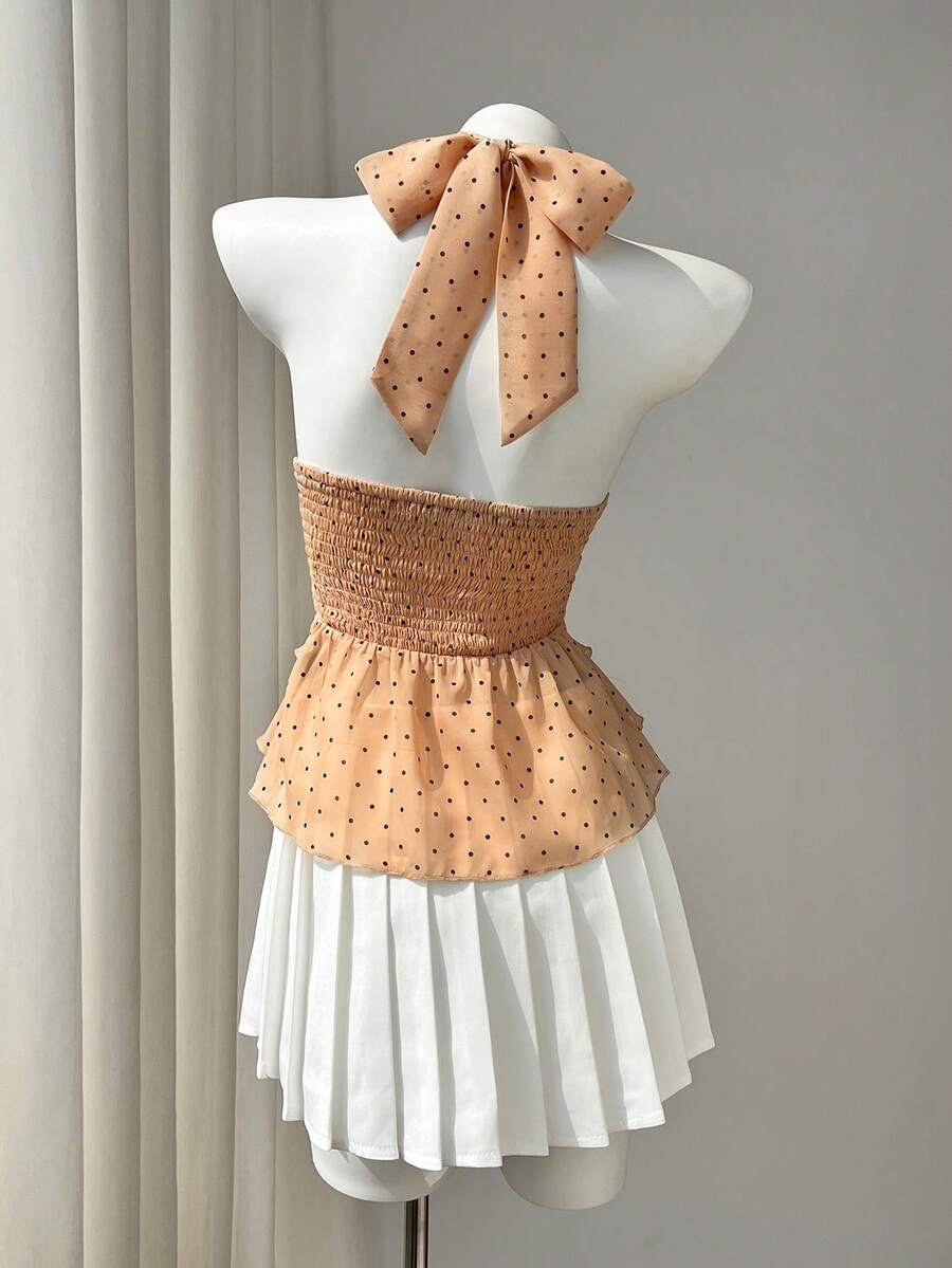 Women's white sleeveless halter neck top featuring pleated fabric, backless tie strap design, and a flared layered ruffle hem.