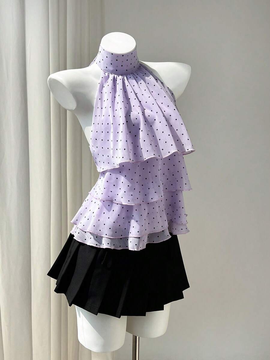 Women's white sleeveless halter neck top featuring pleated fabric, backless tie strap design, and a flared layered ruffle hem.