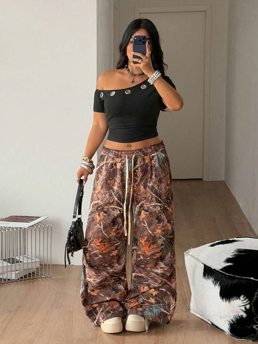Plus size women's one shoulder short sleeve crop top with grommet eyelet detail in high stretch fabric.