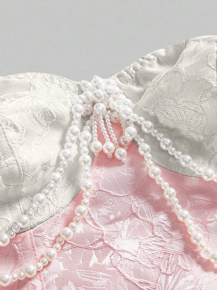 Women's apricot strapless vintage palace style blouse featuring an asymmetrical ruffle hem, backless design, and pearl brooch detail.