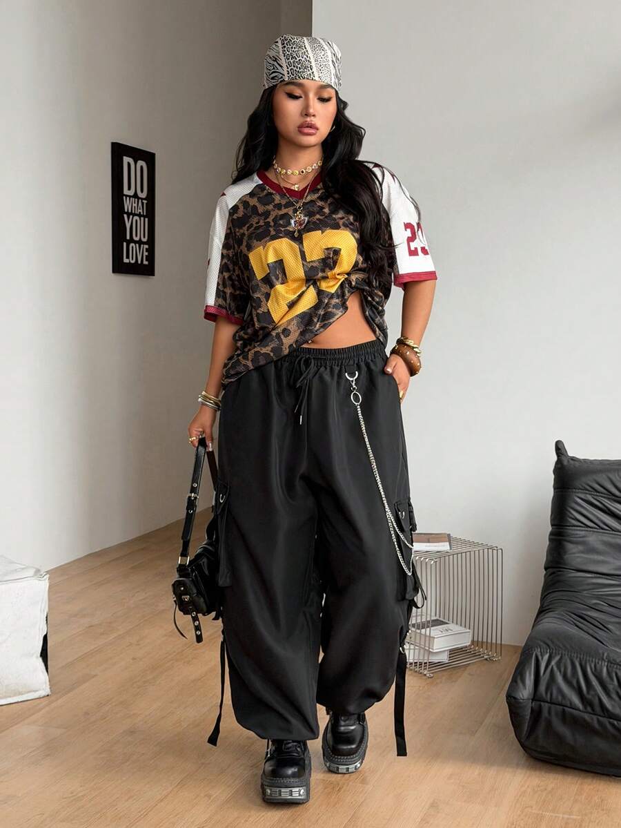 Black plus size cargo pants with drawstring waist and chain accent on loose-fit woven fabric.