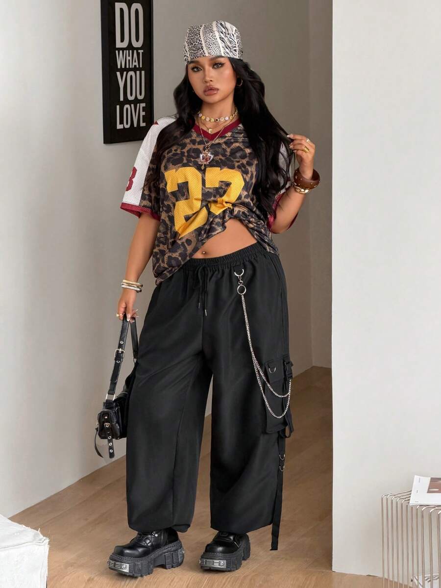 Black plus size cargo pants with drawstring waist and chain accent on loose-fit woven fabric.