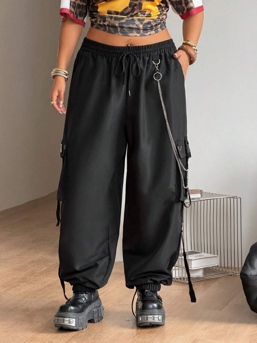 Black plus size cargo pants with drawstring waist and chain accent on loose-fit woven fabric.
