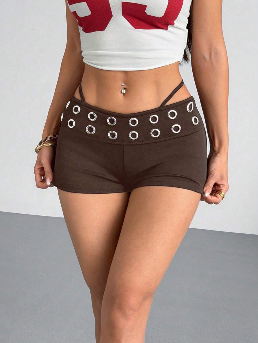 Women's casual track shorts with elastic waist, low-rise mini length, colorblock graphic pattern, and cut-out studded grommet eyelet details.