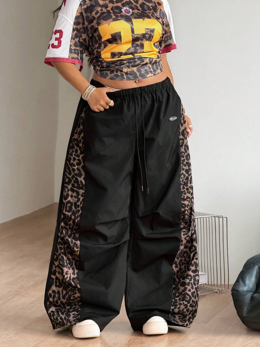 Women's high waist wide leg pants in black featuring leopard print patchwork details and an elastic drawstring waistband.