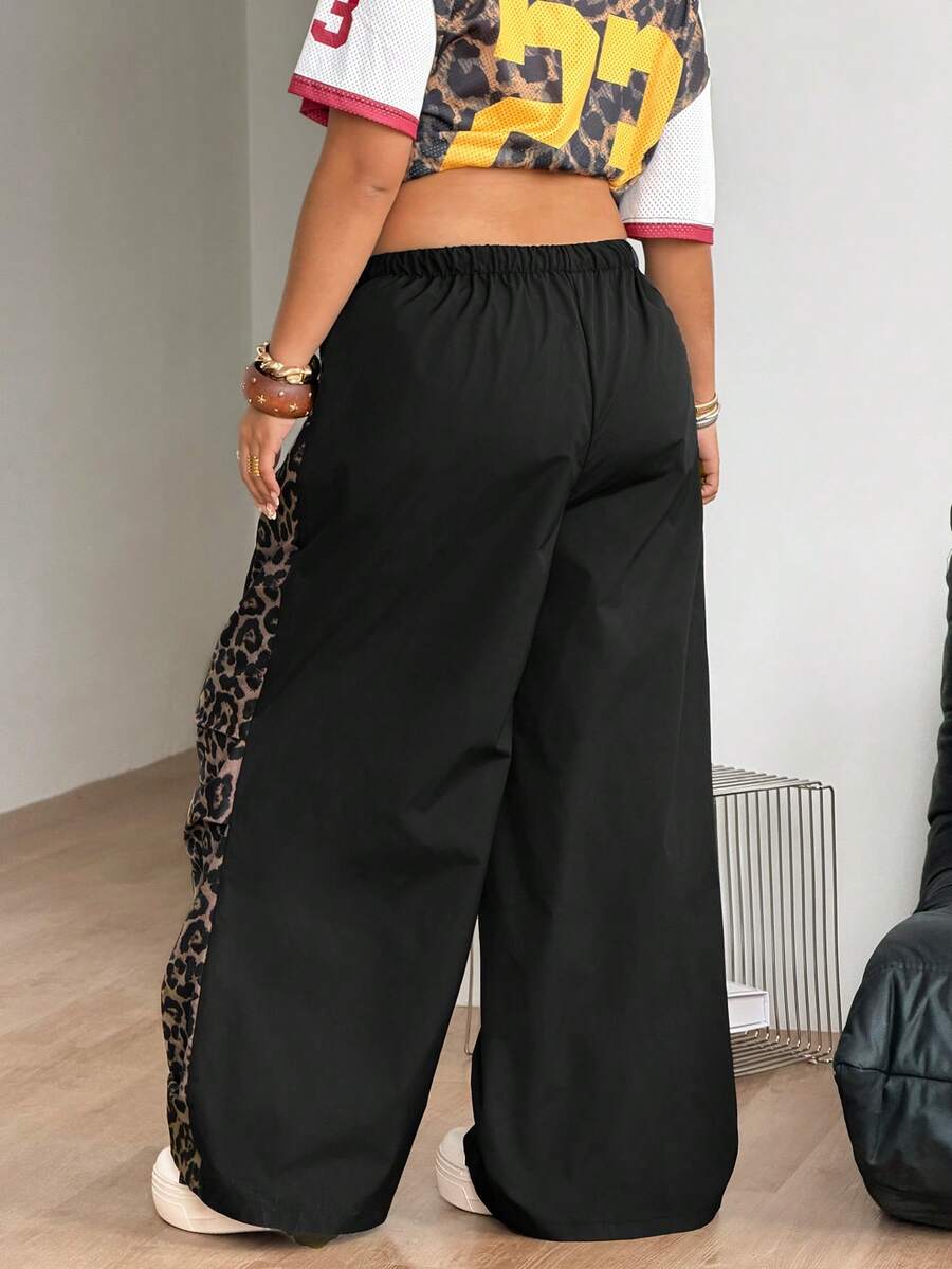 Women's high waist wide leg pants in black featuring leopard print patchwork details and an elastic drawstring waistband.