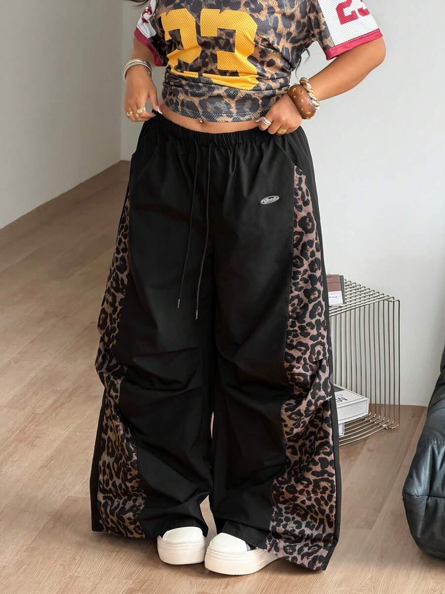 Women's high waist wide leg pants in black featuring leopard print patchwork details and an elastic drawstring waistband.