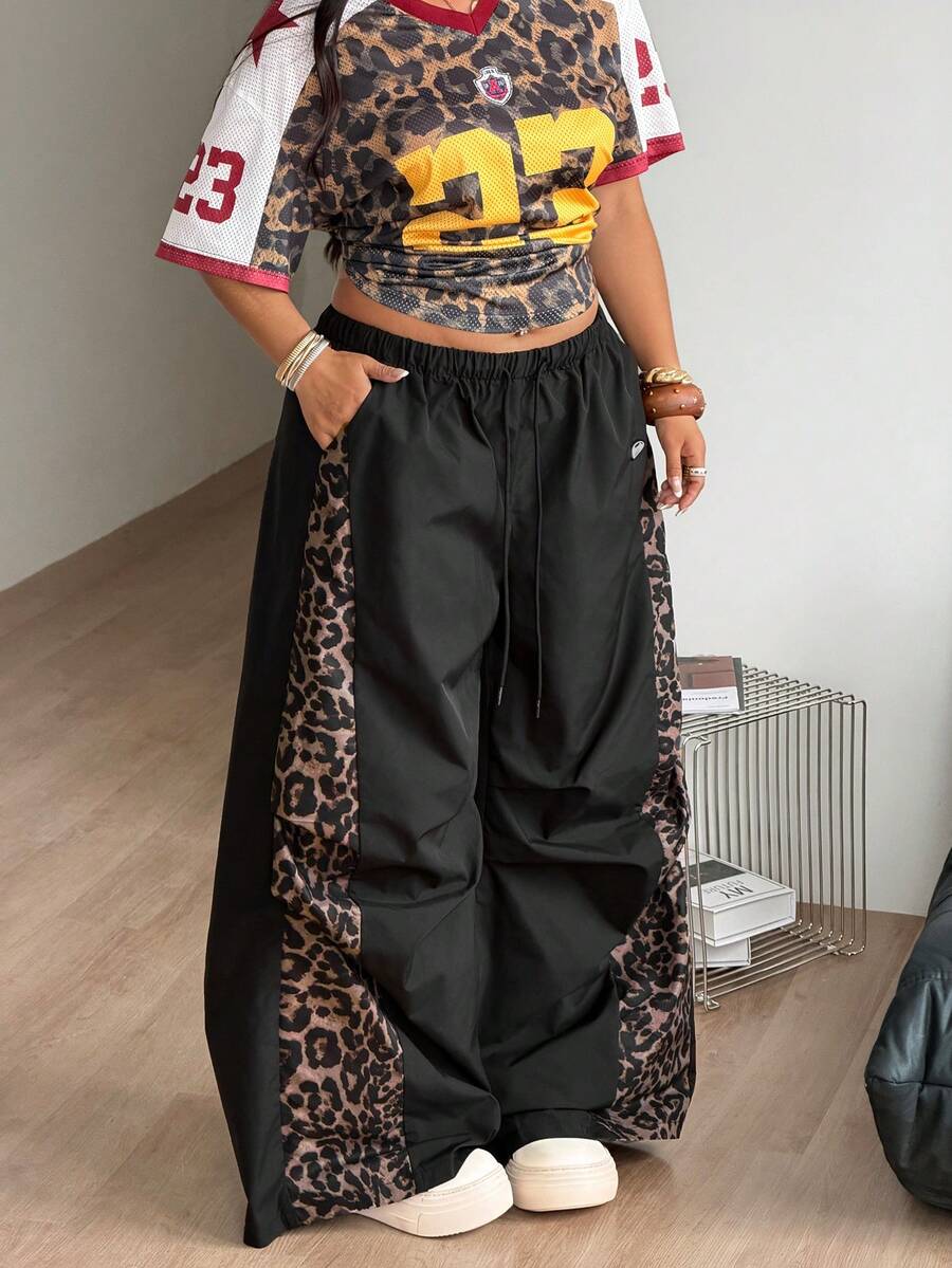 Women's high waist wide leg pants in black featuring leopard print patchwork details and an elastic drawstring waistband.