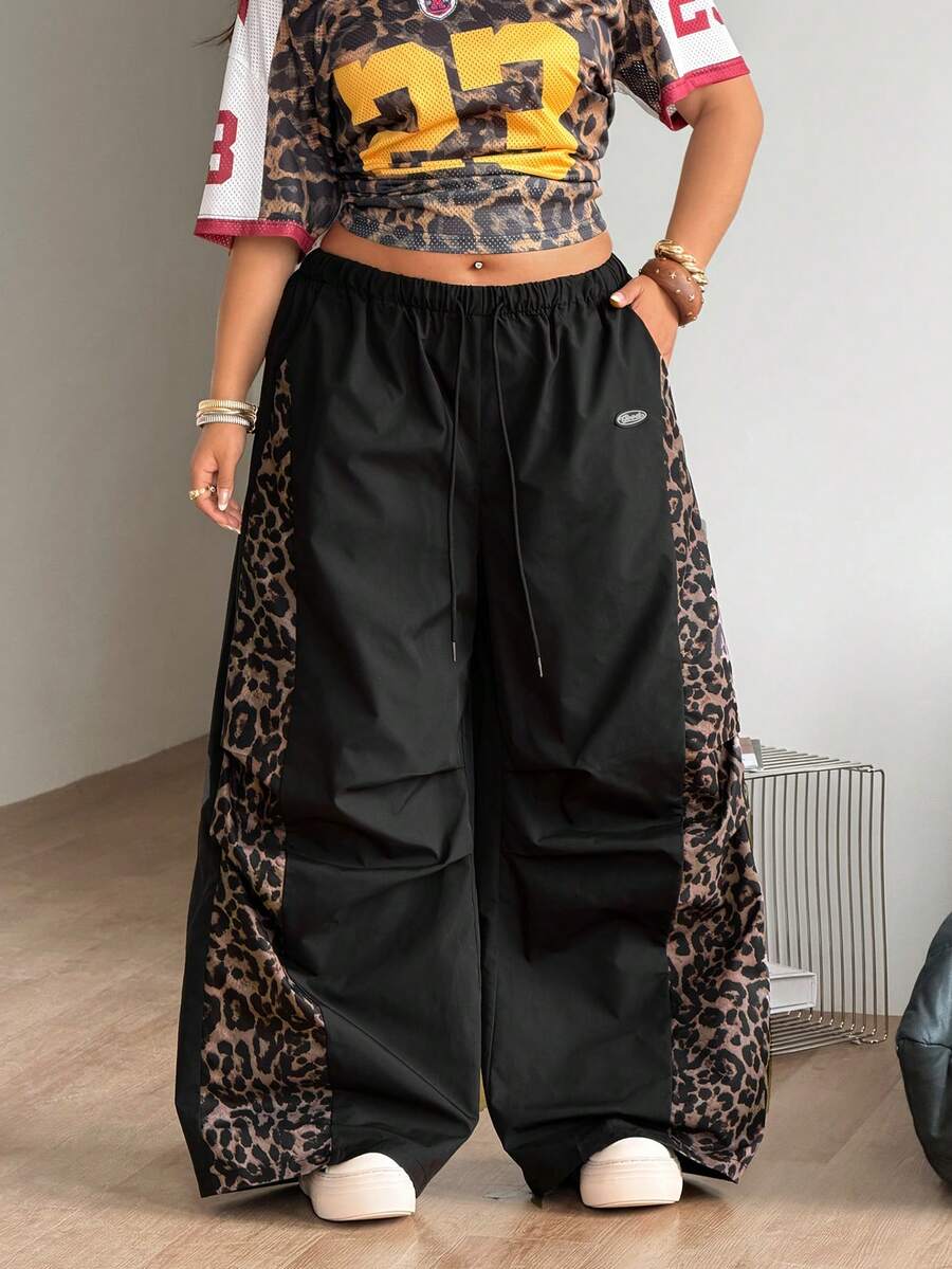 Women's high waist wide leg pants in black featuring leopard print patchwork details and an elastic drawstring waistband.