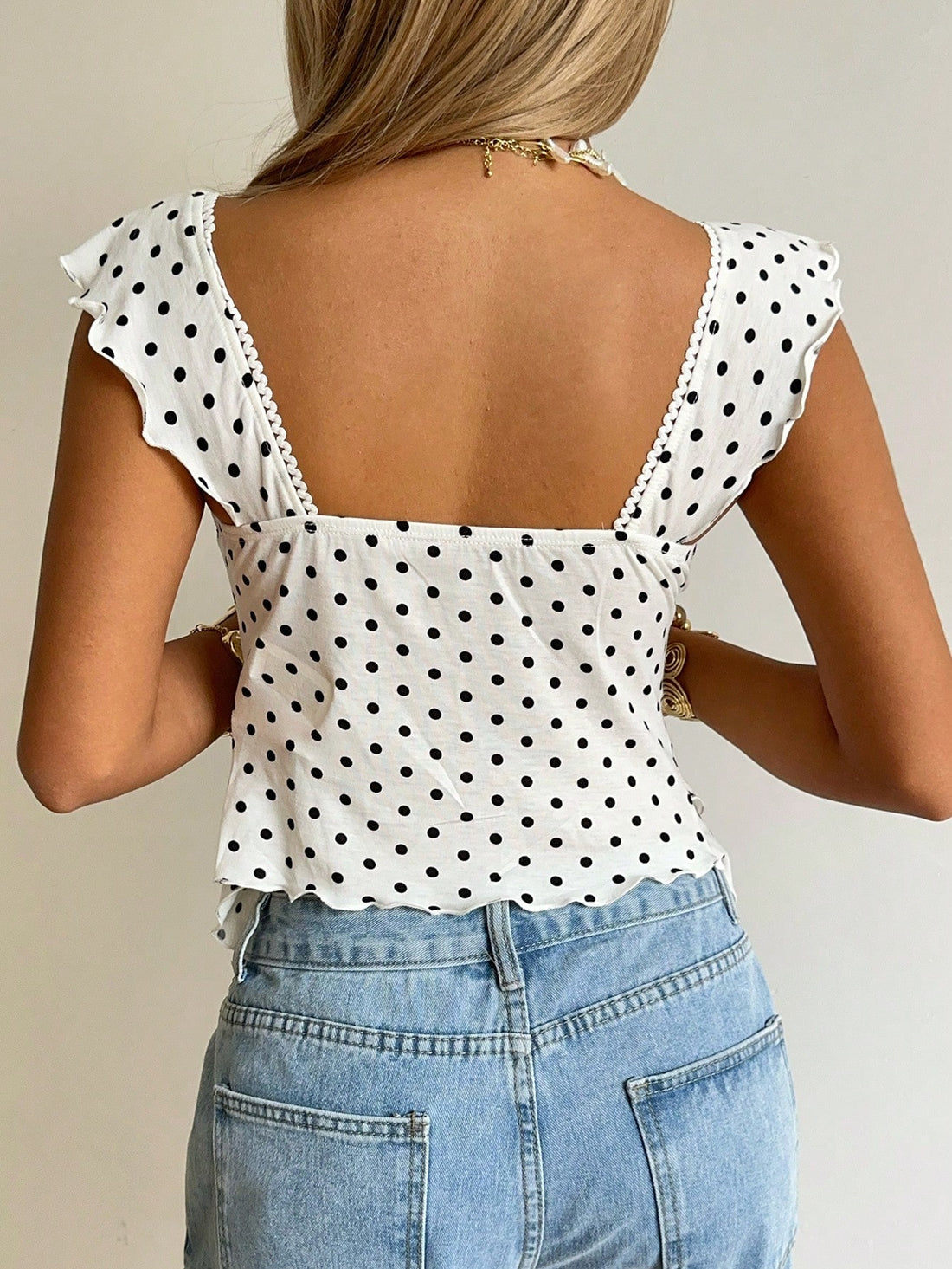 Women's black and white polka dot tank top with sweetheart neckline, twist detail, slim fit, and flared hem