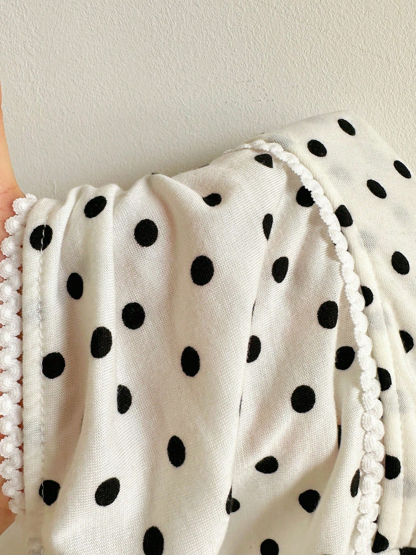 Women's black and white polka dot tank top with sweetheart neckline, twist detail, slim fit, and flared hem