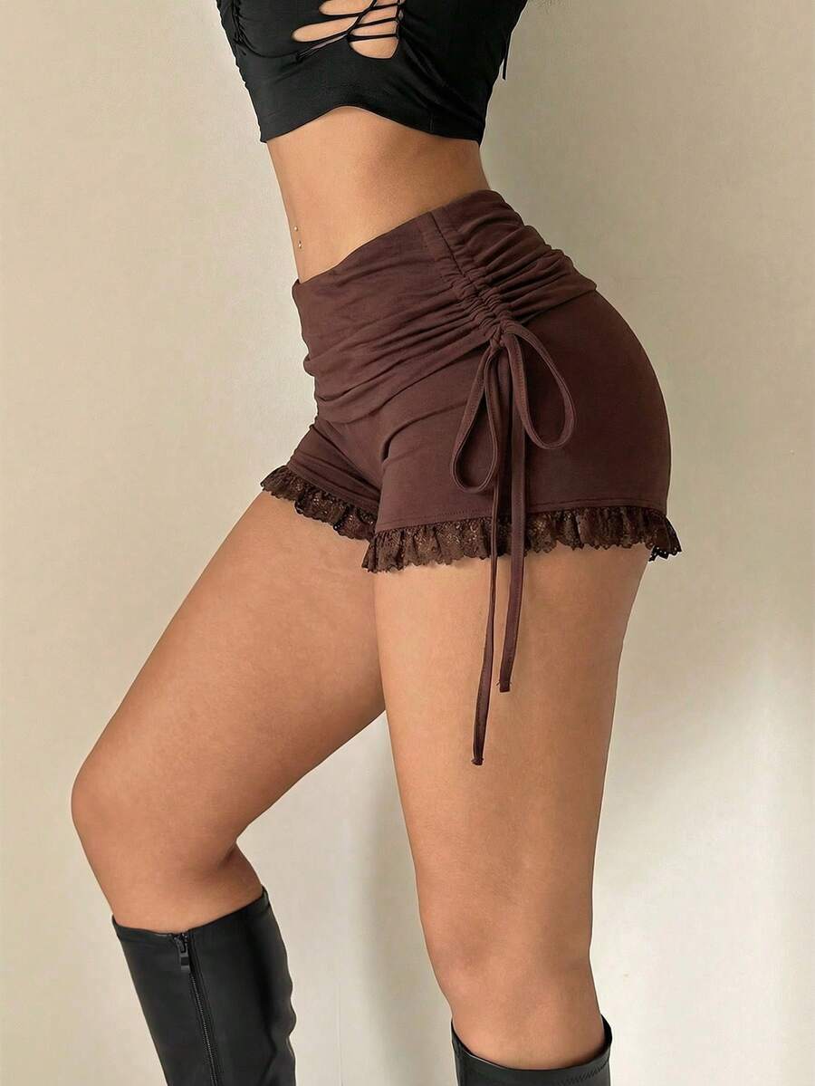 Black Y2K mini shorts with drawstring elastic waist, contrast lace, cut-out details, and ruffled hem